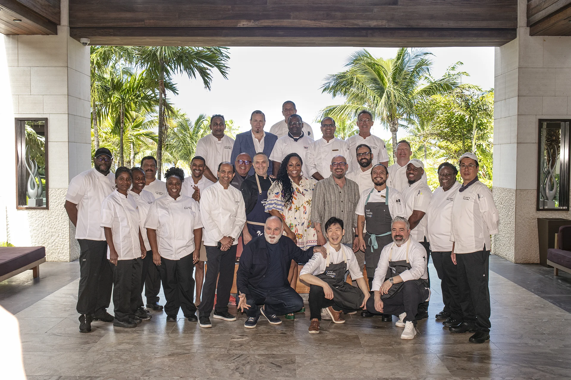 All chefs gathered for a group photo in front of a palm tree background