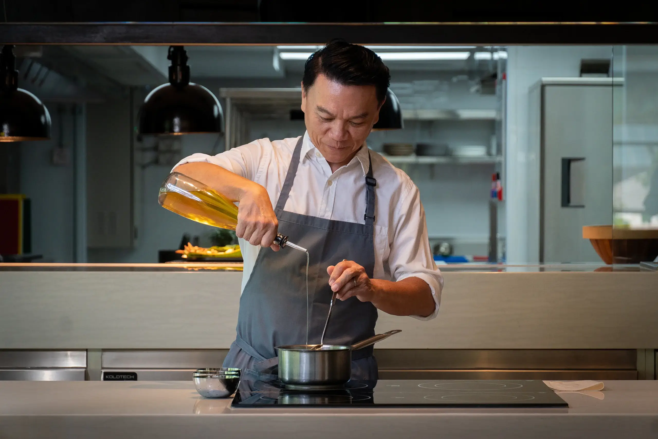 Ian standing center over a pot while pouring oil into the pot.