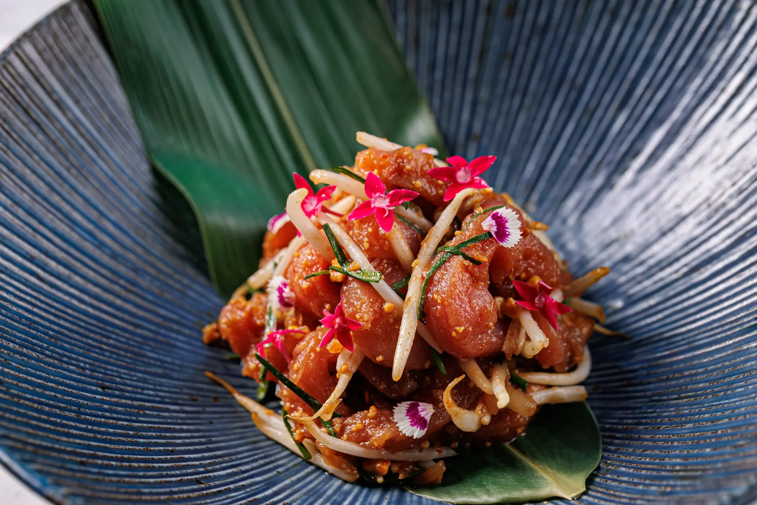 Dish cooked by Ian kitichai. reds and greens on a blue plate.
